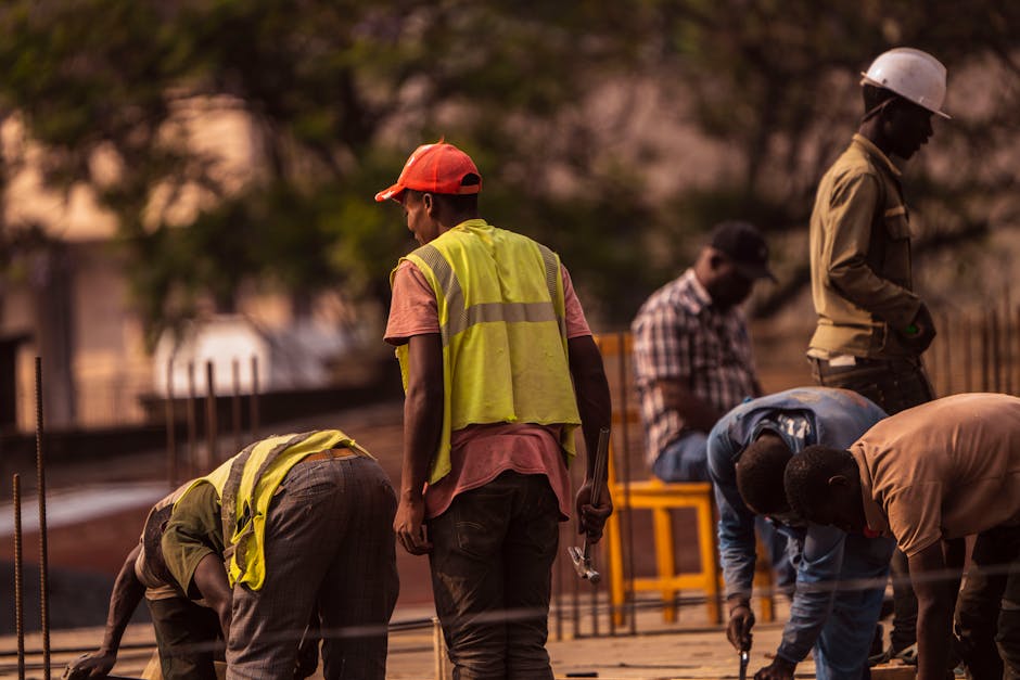 Group of male construction workers on site wearing safety gear during daytime.